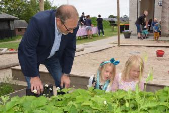 Præsident Erik Kamstrup, Lemvig Rotary Klub, ser på højbed sammen med de interesserede børn, som selv har været med til at tørre frø, så de kan blive til nye planter. Her er det dog jordbær, de ser på.